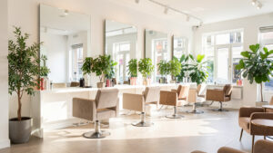 Salon de coiffure moderne et lumineux à Angers, avec fauteuils élégants, grands miroirs, plantes vertes et ambiance professionnelle.